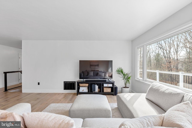 living room featuring visible vents, baseboards, and light wood finished floors