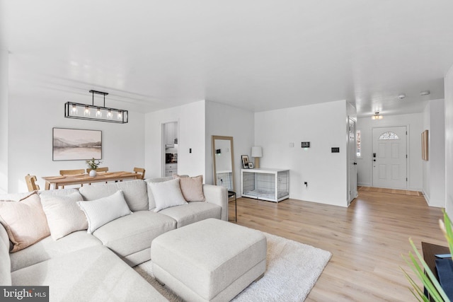 living area with light wood-type flooring and an inviting chandelier