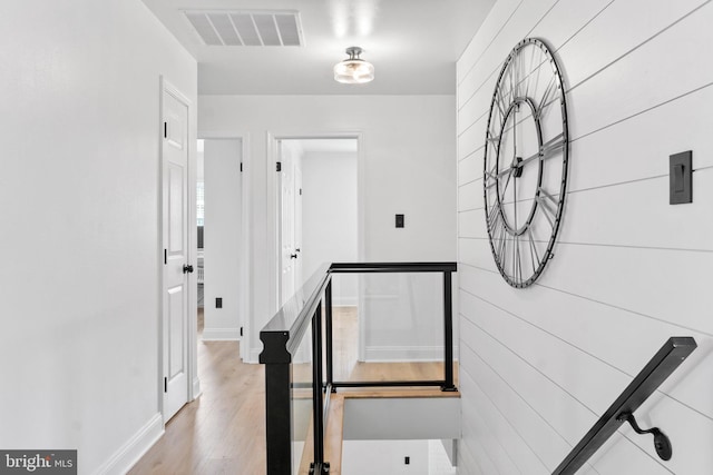 staircase featuring wood finished floors, visible vents, and baseboards