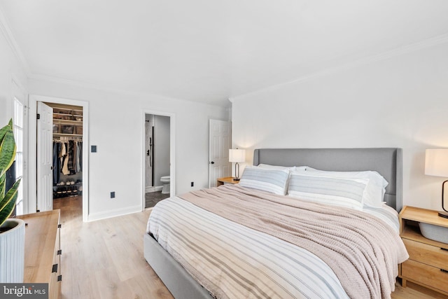 bedroom with baseboards, ornamental molding, light wood-style floors, a closet, and a walk in closet