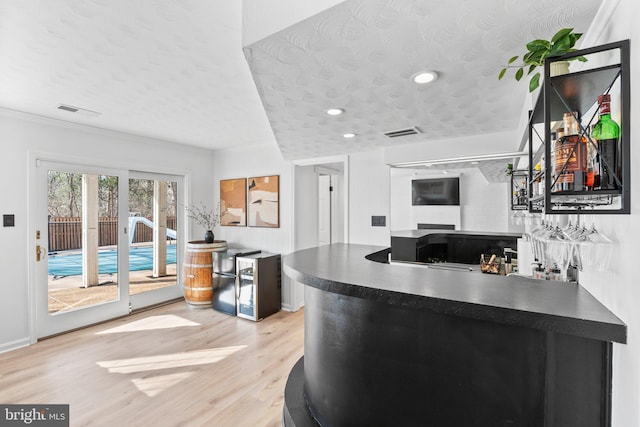 kitchen with dark countertops, light wood-style flooring, visible vents, and a textured ceiling