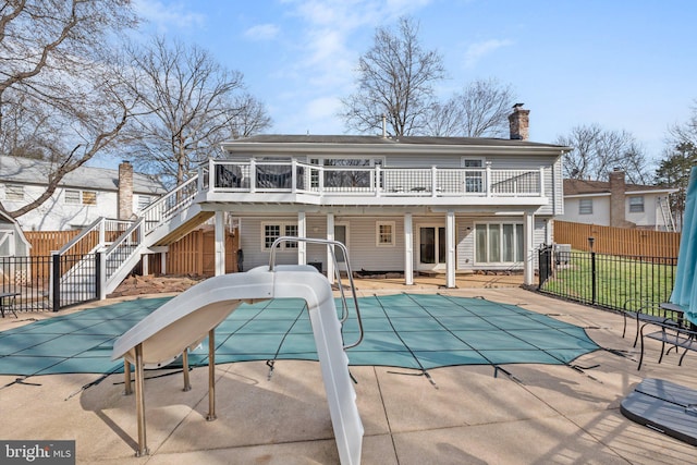 back of house featuring a patio, fence, a fenced in pool, a chimney, and stairs