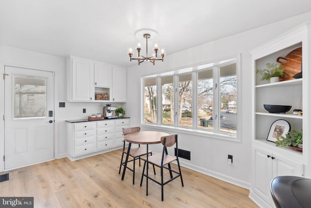 dining space with visible vents, baseboards, light wood-style floors, and an inviting chandelier