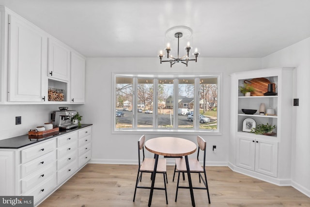 dining area with baseboards, light wood-style floors, and an inviting chandelier