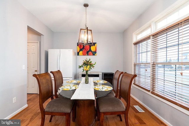 dining area with visible vents, baseboards, an inviting chandelier, and light wood finished floors