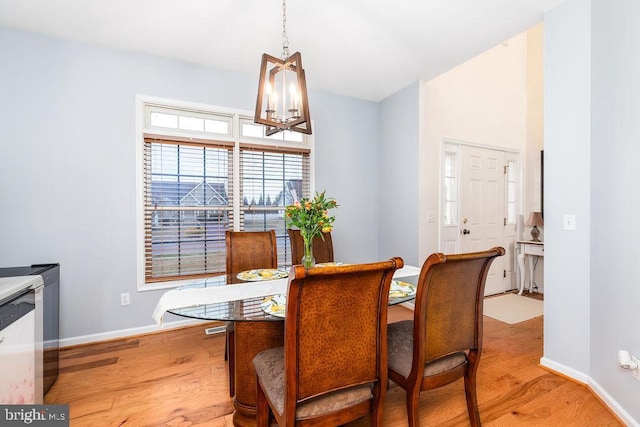 dining space with baseboards, lofted ceiling, and light wood-style flooring