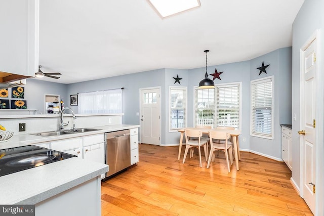 kitchen with light wood finished floors, dishwasher, light countertops, white cabinets, and a sink