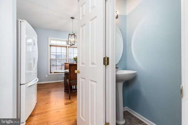 bathroom featuring a notable chandelier, wood finished floors, and baseboards