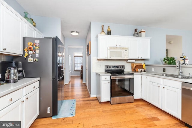 kitchen with a sink, white cabinetry, appliances with stainless steel finishes, light wood finished floors, and light countertops