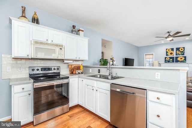 kitchen featuring backsplash, appliances with stainless steel finishes, a peninsula, a ceiling fan, and a sink