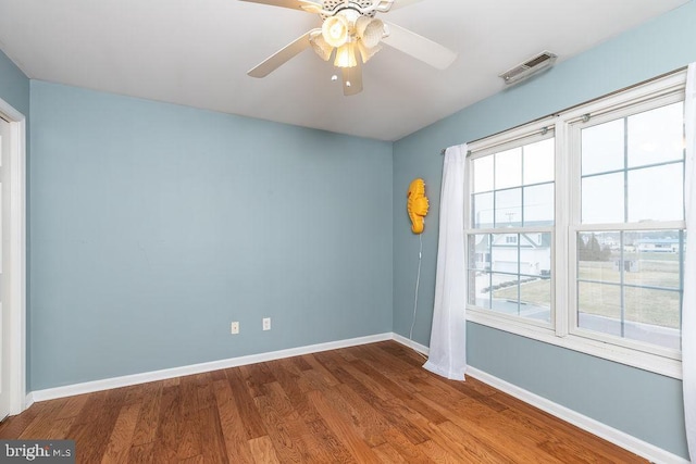 empty room with visible vents, baseboards, wood finished floors, and a ceiling fan