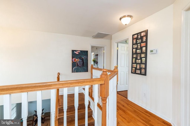 hallway featuring an upstairs landing, visible vents, light wood finished floors, and baseboards