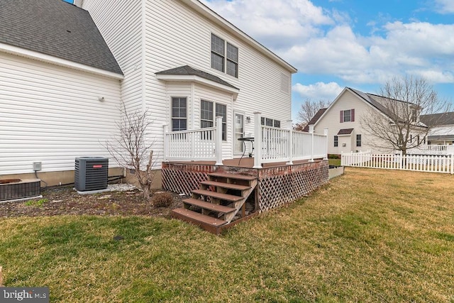 rear view of property featuring roof with shingles, a wooden deck, a yard, central air condition unit, and fence private yard