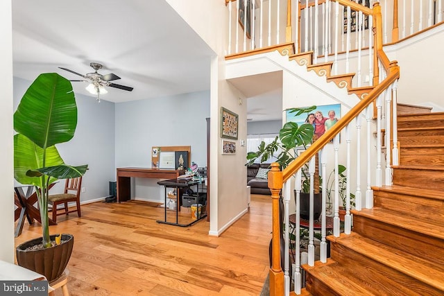 stairway with a ceiling fan, wood finished floors, and baseboards