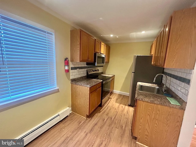 kitchen featuring a sink, a baseboard heating unit, dark countertops, stainless steel appliances, and light wood finished floors