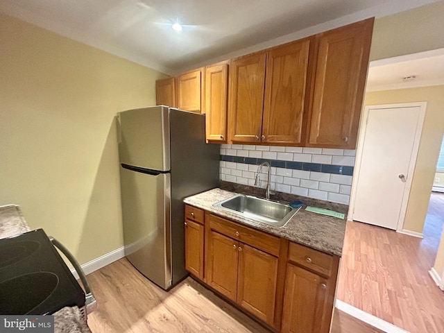 kitchen with a sink, stainless steel appliances, decorative backsplash, and light wood finished floors