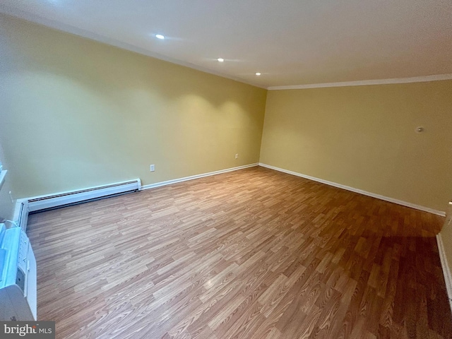 unfurnished room featuring baseboard heating, crown molding, baseboards, and wood finished floors