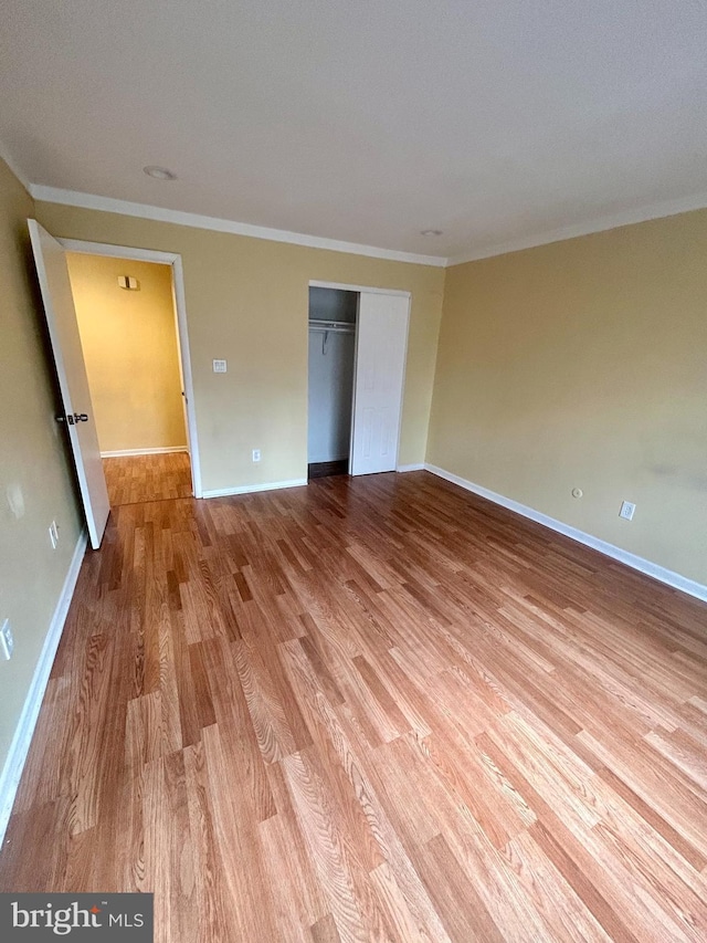 unfurnished bedroom with crown molding, light wood-style floors, and baseboards