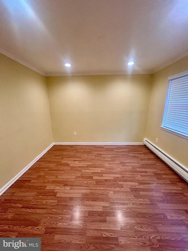 below grade area featuring a baseboard heating unit, recessed lighting, wood finished floors, and baseboards