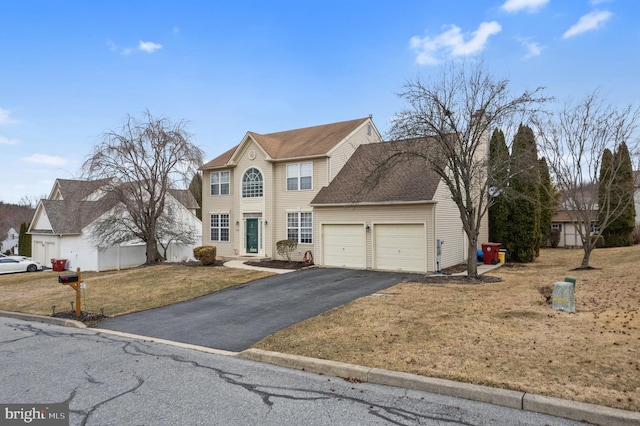 colonial inspired home with aphalt driveway, a garage, a front yard, and a shingled roof