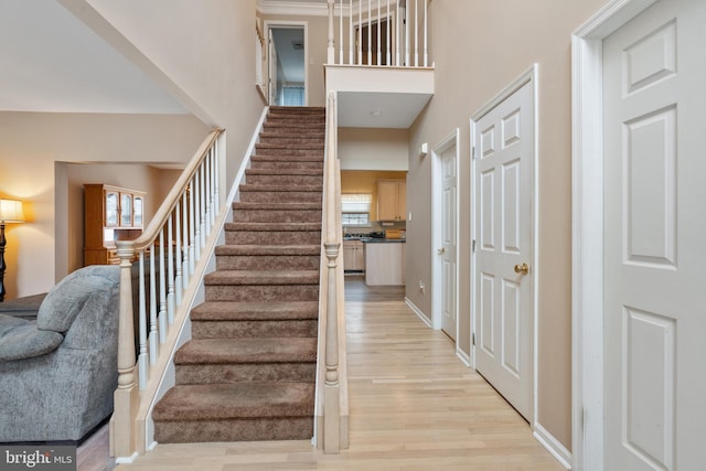 stairs with a towering ceiling, baseboards, and wood finished floors