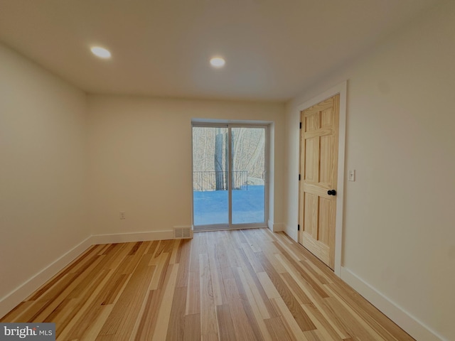 spare room featuring visible vents, baseboards, and light wood finished floors