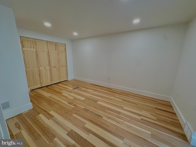 unfurnished bedroom featuring visible vents, baseboards, a closet, and light wood finished floors