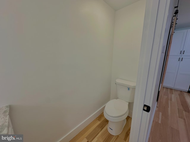 bathroom with baseboards, toilet, and wood finished floors