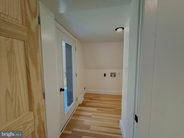 hall with light wood-style flooring, baseboards, and vaulted ceiling