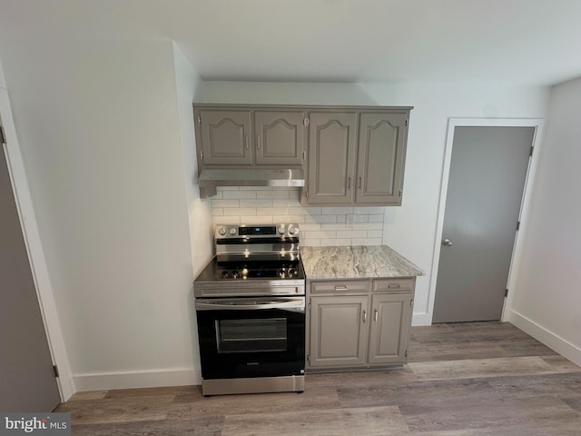 kitchen featuring under cabinet range hood, stainless steel electric range oven, tasteful backsplash, and gray cabinetry