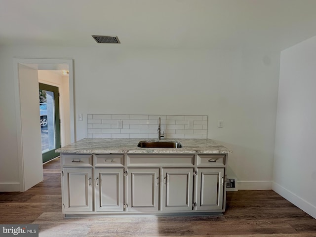 interior space featuring visible vents, a sink, baseboards, decorative backsplash, and dark wood-style flooring