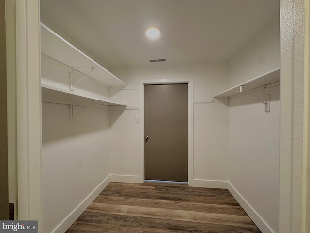 spacious closet with dark wood-style floors and visible vents