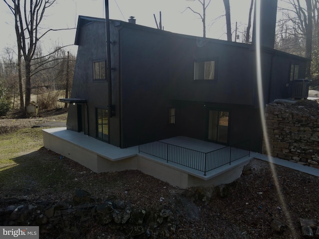 rear view of house with stucco siding and central AC unit