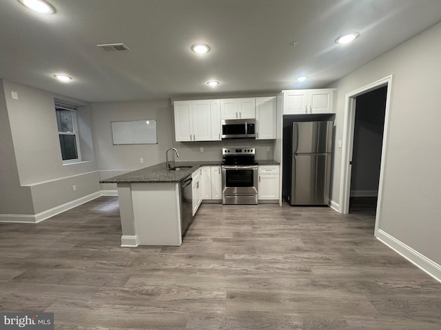 kitchen featuring visible vents, a sink, wood finished floors, white cabinetry, and appliances with stainless steel finishes