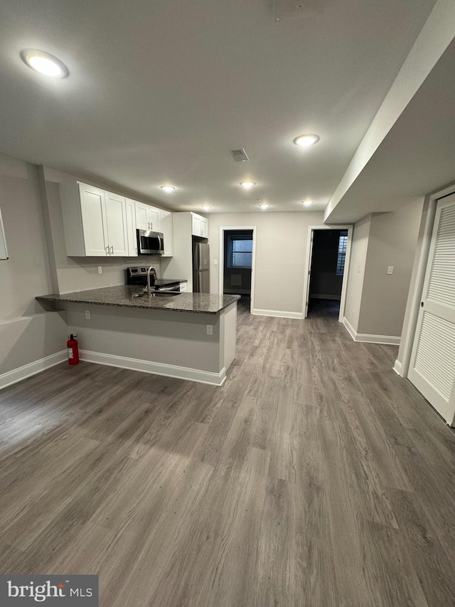 kitchen featuring a peninsula, a sink, stainless steel appliances, dark wood-type flooring, and white cabinets