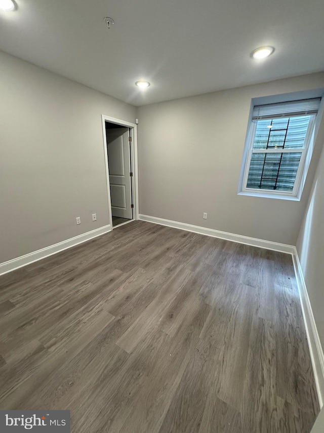 empty room with dark wood finished floors and baseboards