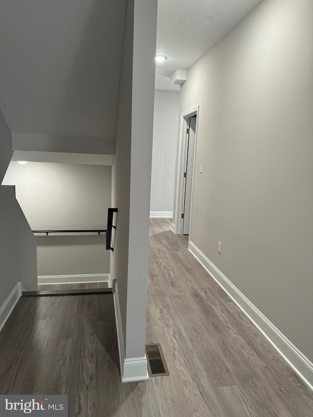 corridor featuring visible vents, baseboards, and wood finished floors