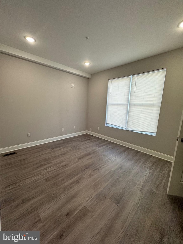 empty room featuring recessed lighting, dark wood-style floors, and baseboards