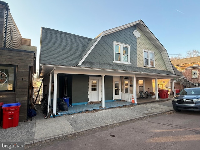 view of front of house with a gambrel roof, roof with shingles, and a porch