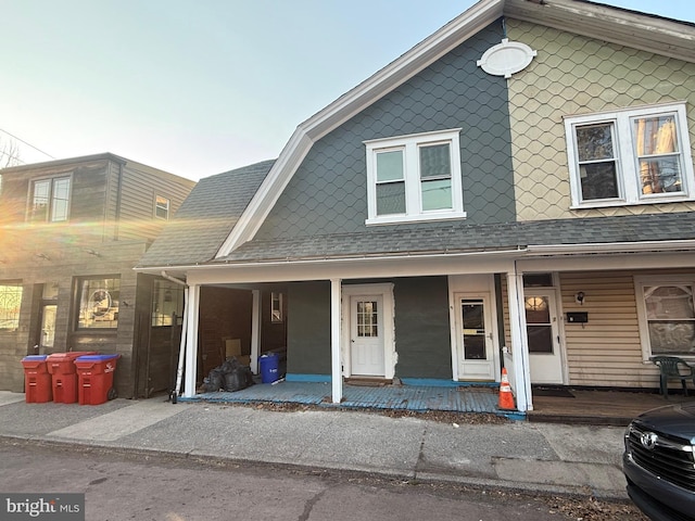 townhome / multi-family property with covered porch, a gambrel roof, and a shingled roof