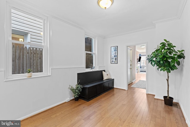 interior space featuring light wood-type flooring, baseboards, and crown molding