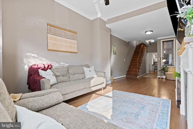 living room with crown molding, ceiling fan, baseboards, stairs, and hardwood / wood-style flooring