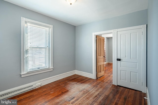 unfurnished bedroom with baseboards, baseboard heating, and wood finished floors