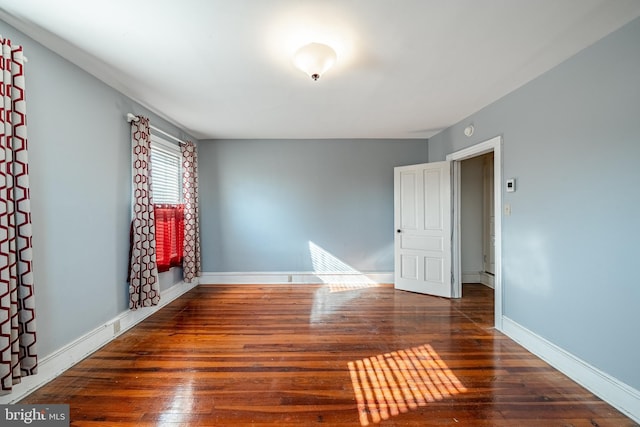 spare room with baseboards and hardwood / wood-style floors