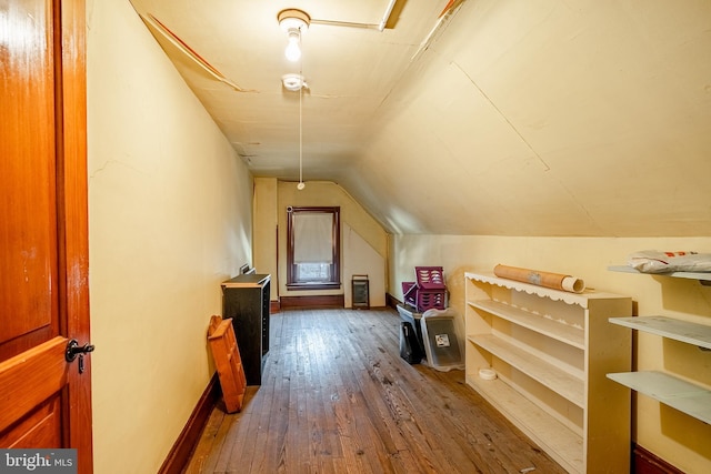 additional living space with hardwood / wood-style flooring, baseboards, and vaulted ceiling