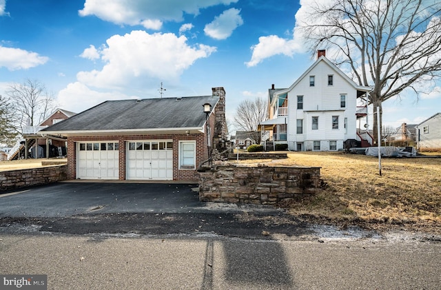 exterior space with driveway, a chimney, and an attached garage