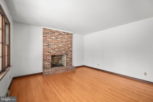 13360 Fredericksburg Tpke, Woodford, VA 22580 - unfurnished living room with baseboards, wood finished floors, a baseboard heating unit, and a brick fireplace
