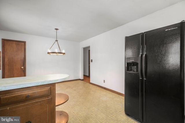 13360 Fredericksburg Tpke, Woodford, VA 22580 - kitchen with light countertops, pendant lighting, light floors, black fridge, and baseboards