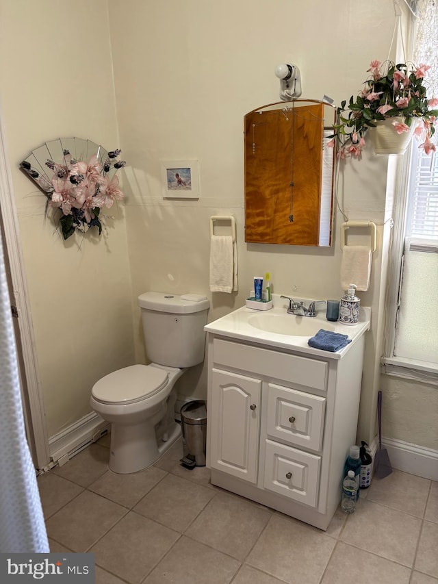 half bath with vanity, toilet, baseboards, and tile patterned flooring