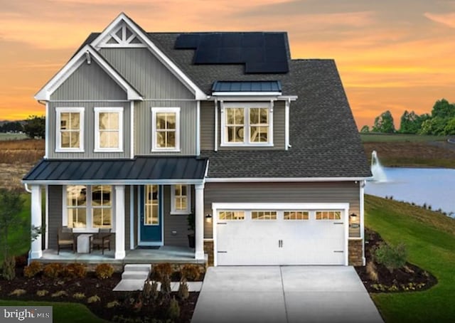 view of front of house featuring covered porch, solar panels, driveway, and a standing seam roof